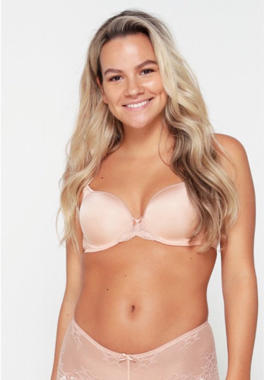 Model met blond haar draagt een beige beha met kanten details op de bandjes en een strikje.