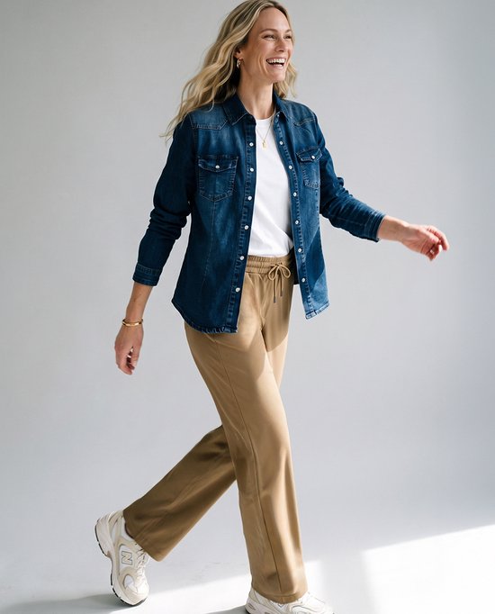 Model in spijkerblouse, wit t-shirt en bruine travelstof broek met elastische tailleband.