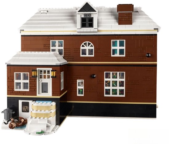 LEGO-huis met bruine bakstenen, witte dakranden, schoorsteen en sneeuw, met een figuur liggend buiten.