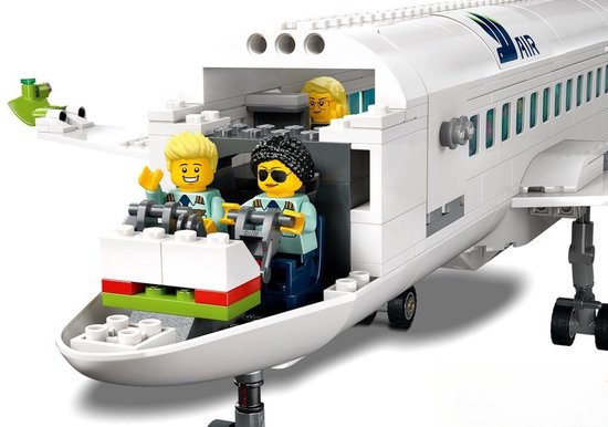 Twee LEGO piloten in de cockpit van een passagiersvliegtuig, met passagiers op de achtergrond.