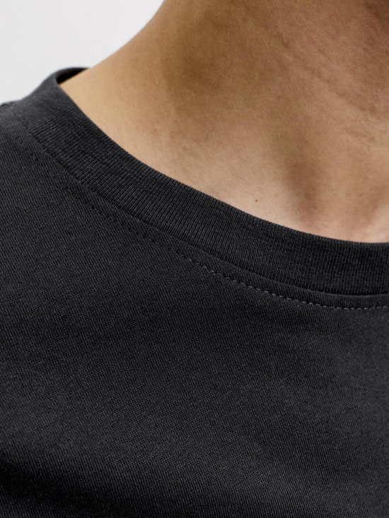 Close-up van de ronde hals van een zwarte t-shirt met zichtbare naden.