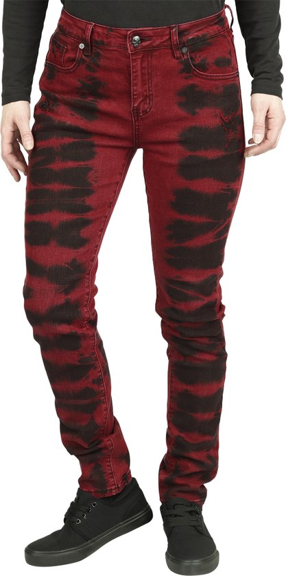 Dames, donkerrode skinny jeans met horizontale zwarte batikprint, gedragen met zwarte schoenen.