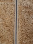 Detail van de ritssluiting op een camelkleurig fleece vest.