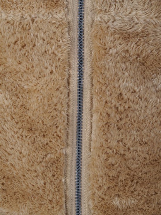 Detail van de ritssluiting op een camelkleurig fleece vest.