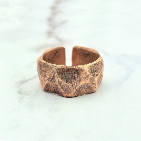 Bague couleur cuivre avec un motif incurvé, facetté et une ouverture.