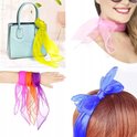 Een lichtblauwe handtas met een felgele chiffon sjaal eromheen gebonden. Een pols met vier gekleurde sjaals: roze, oranje, geel en paars. Een vrouw met een roze sjaal om haar nek en een blauwe sjaal als haarband.