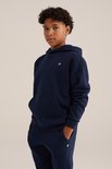 Jongen met donkerblauwe hoodie met kleine witte vogelembroidery op de borst. Broek met dezelfde embroidery.