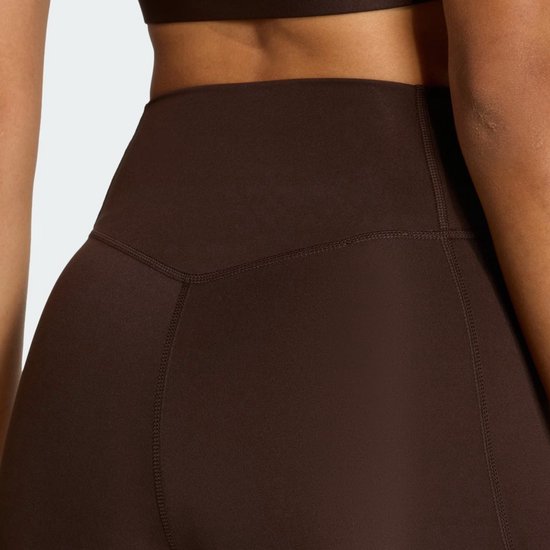 Close-up van de tailleband van een donkerbruine legging met stiksels.