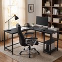 Zwart hoekbureau met leren bureaustoel, computer, lamp en boekenplank.