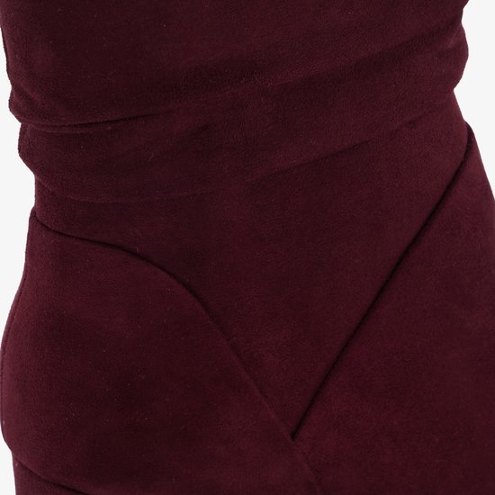 Detail van bordeauxrode enkellaars van suède met gedrapeerde stof en schuine naden.