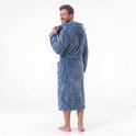 Homme en long peignoir bleu à capuche, debout de dos. Il tire la capuche vers lui.