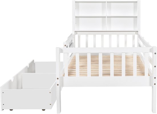 Wit kinderbed met open vakken in het hoofdeinde en twee uittrekbare laden aan de zijkant.
