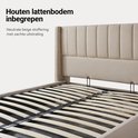 Dichtbij detailopname van de houten lattenbodem van een beige gestoffeerd bed. Het frame is zichtbaar met het opbergmechanisme.