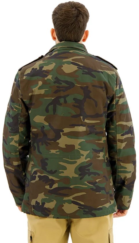 Man met de rug naar de camera, draagt een groene camouflage jas. Hij draagt een kaki broek.