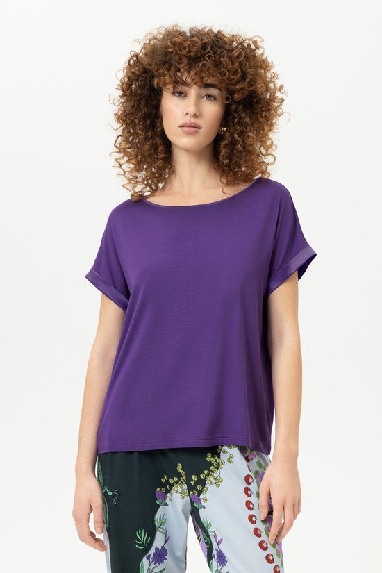 Vrouw met krullend haar in paars T-shirt en kleurrijke broek