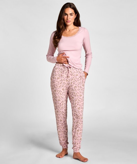 Model draagt een roze pyjamaset met bloemenprint. De broek heeft strikdetail.