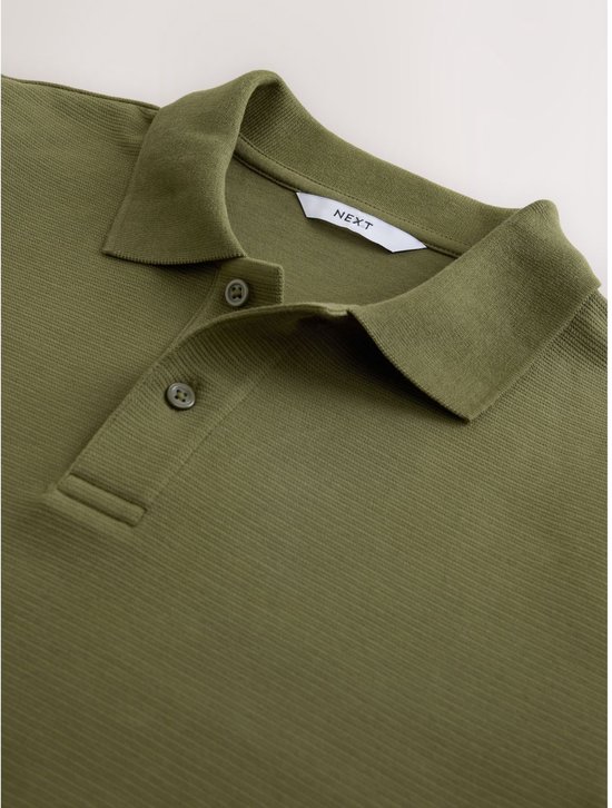Detail van de kraag en knoopsluiting van het olijfgroene poloshirt met NEXT-label.