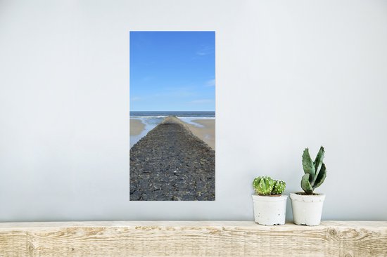 Een poster met stenen dam en zee hangt boven een houten plank.