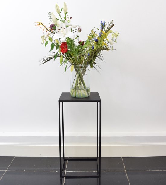 Zwarte metalen zuil met een boeket bloemen in een glazen vaas.