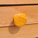 Oranje gestreepte knop op een houten lade van een konijnenhok.