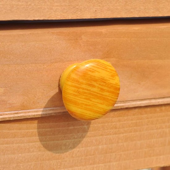 Oranje gestreepte knop op een houten lade van een konijnenhok.
