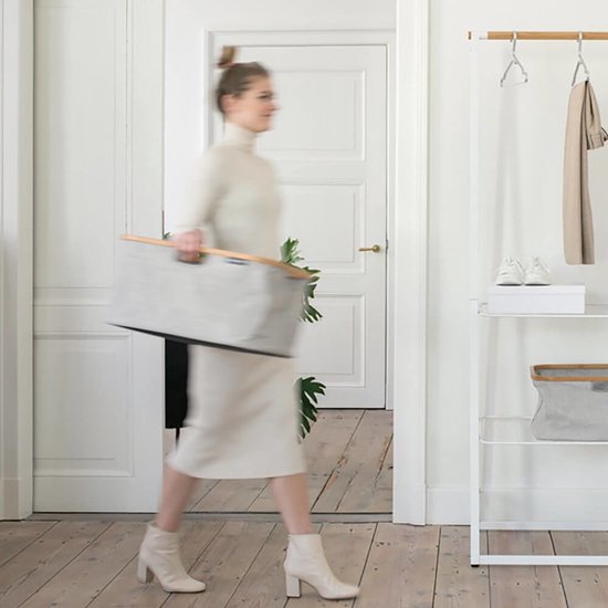 Vrouw draagt grijze Brabantia wasmand met bamboe frame.