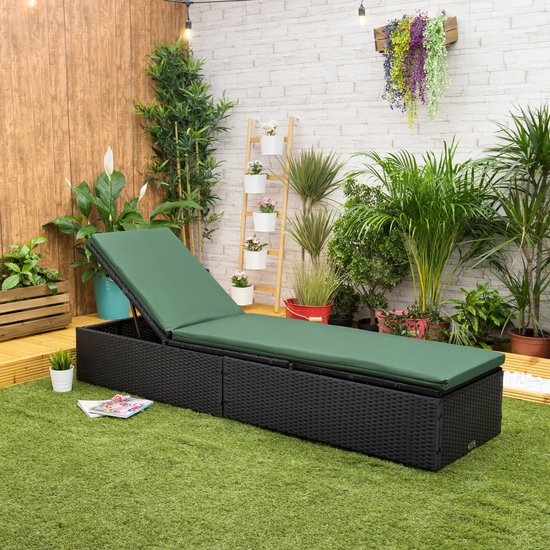 Een donkergroen ligstoelkussen op een zwarte wicker ligstoel in een tuinomgeving.