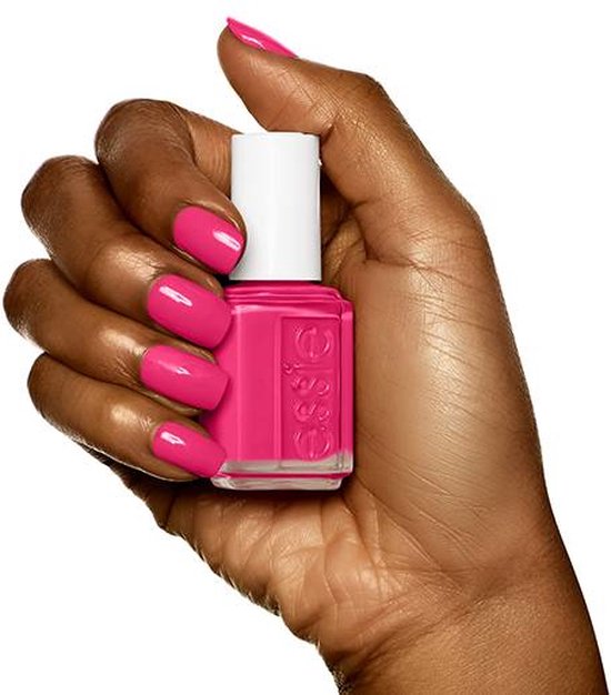Donkere hand houdt essie nagellakflesje met felroze lak. Nagellak is felroze.