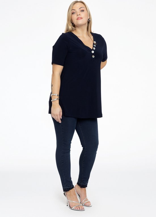 Model van opzij met donkerblauwe spijkerbroek met hoge taille en rafelige zoom.