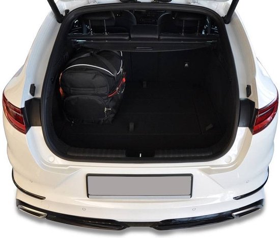 Zwarte reistas met witte en rode accenten in de kofferbak van een witte auto.