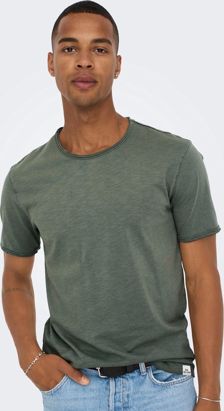 Close-up van een man met een olijfgroen T-shirt en een riem in een lichtblauwe jeans.