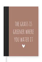 Notitieboek - Schrijfboek - Engelse quote "The grass is greener where you water it" met een hartje op een bruine achtergrond - Notitieboekje klein - A5 formaat - Schrijfblok