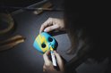 Hand tekent gele lijnen op blauw masker met stift. Donkere achtergrond.