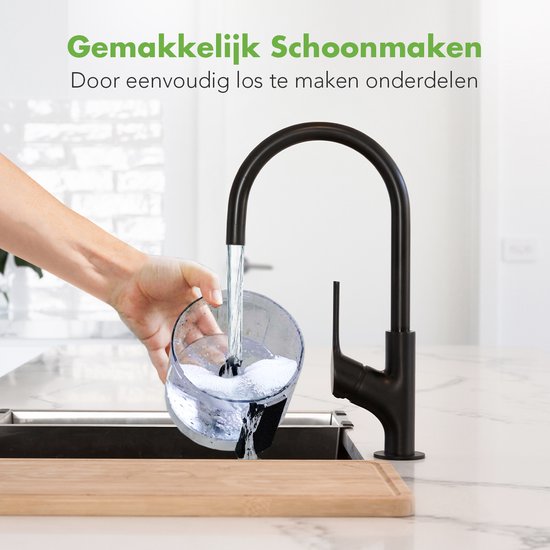 Hand spoelt een deel van de keukenmachine onder een zwarte kraan in een gootsteen.