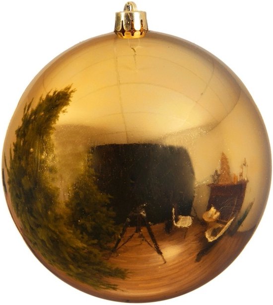 Boule de Noël dorée brillante en plastique avec un capuchon doré. La boule reflète un sapin de Noël.