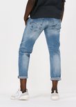 Model in een lichtblauwe G-Star jeans met opgerolde broekspijpen en witte sneakers.