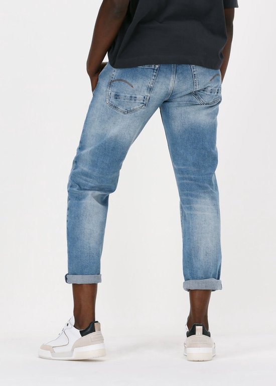 Model in een lichtblauwe G-Star jeans met opgerolde broekspijpen en witte sneakers.