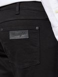 Detail van de achterzak van een zwarte Wrangler jeans met een zwart leren logo.