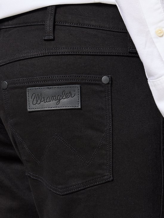 Detail van de achterzak van een zwarte Wrangler jeans met een zwart leren logo.