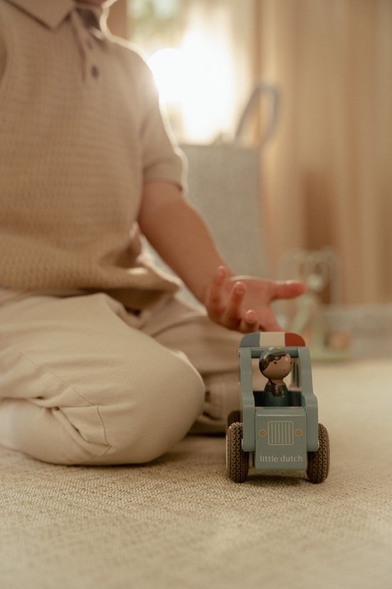 Blauwe houten politieauto met poppetje, speelt een jongetje ermee.