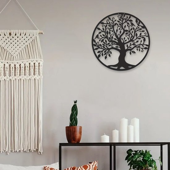 L'arbre de vie en métal noir est suspendu à un mur gris à côté d'une tenture murale en macramé et de chandeliers.