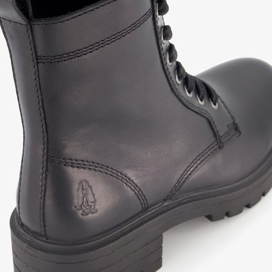 Detail van de gestikte naden en het Hush Puppies logo op een zwarte leren veterboot.