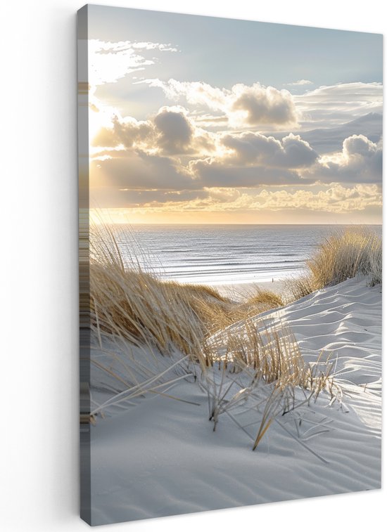 Zonsondergang over de duinen met gras, strand en de zee. De zon schijnt door de wolken.