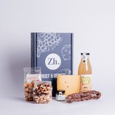 Een borrelpakket met kaas, worst, sap en snacks, met een doos van Zuivelhoeve.
