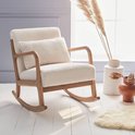 Schommelstoel met een licht houten frame en crème bouclé bekleding, in een lichte kamer met decoratie.