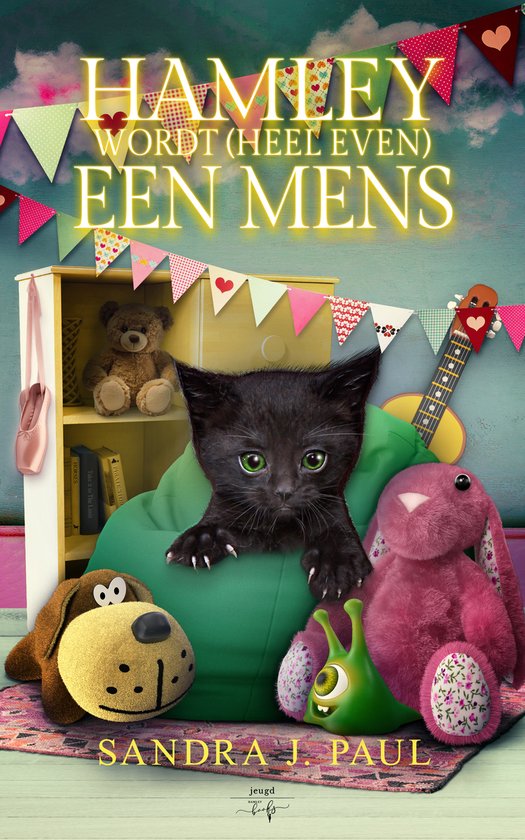 Een zwart katje met groene ogen kijkt vanuit een groene zitzak naar voren. Om hem heen liggen knuffels.