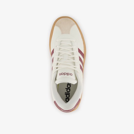 Bovenkant van een witte damessneaker met bordeauxrode strepen en Adidas-logo op de tong.