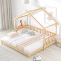 Houten huisbed met spijlen en matras, versierd met knuffels en een deken, in een kinderkamer met een print aan de muur.