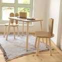 Houten kindertafel en stoelen met konijnenoren op een gestreepte deken bij een raam.