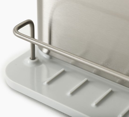 Close-up van de zilverkleurige Joseph Joseph gootsteen organizer op een beige onderzetter.